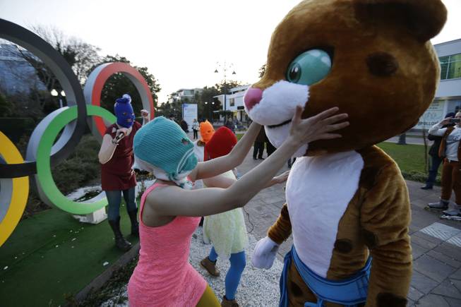 Pussy Riot member Nadezhda Tolokonnikova in the aqua balaclava, left, interacts with an Olympic mascot while the group perform next to the Olympic rings in Sochi, Russia, on Wednesday, Feb. 19, 2014. 