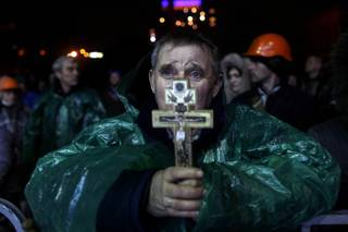An anti-government protester holds a crucifix as he prays at Independence Square in Kiev, Ukraine, Thursday, Feb. 20, 2014. Ukraine's protest leaders and the president they aim to oust called a truce Wednesday, just hours after the military raised fears of a widespread crackdown with a vow to defeat 
