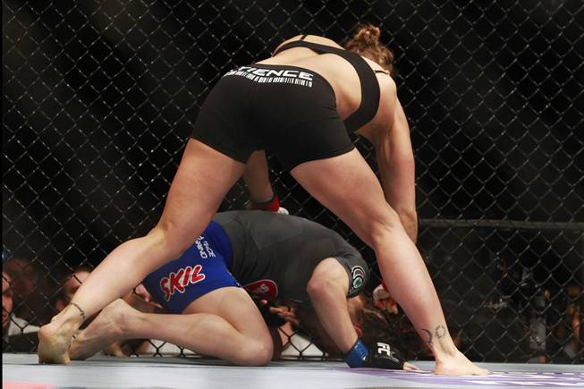 Ronda Rousey pounds Sara McMann after sending her to the mat during their fight at UFC 170 Saturday, Feb. 22, 2014 at the Mandalay Bay Events Center. Rousey won by TKO in the first round with a knee to the McMann's liver.