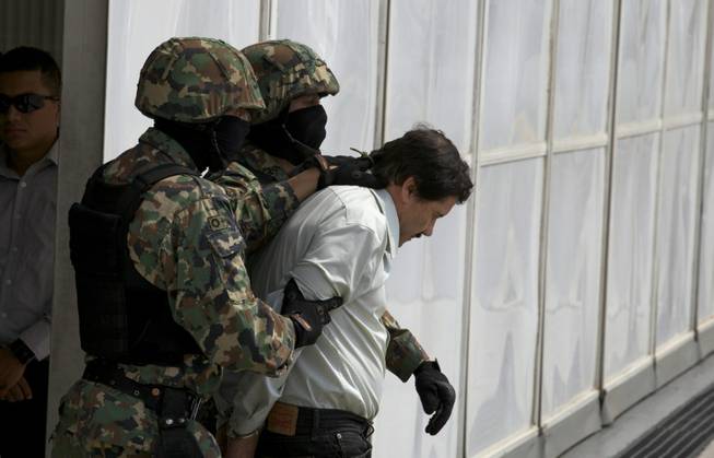 Joaquin "El Chapo" Guzman is escorted to a helicopter in handcuffs by Mexican navy marines at a navy hangar in Mexico City, Saturday, Feb. 22, 2014. A senior U.S. law enforcement official said Saturday that Guzman, the head of Mexico's Sinaloa Cartel, was captured alive overnight in the beach resort town of Mazatlan. 