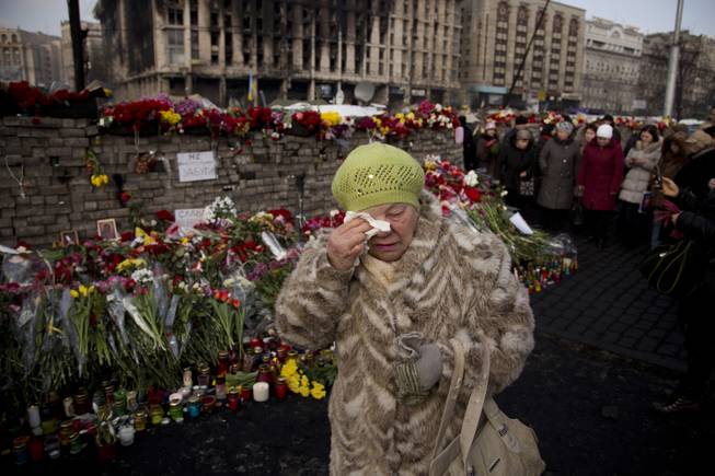 A woman cries near a memorial for the people killed in clashes with the police at Independence Square in Kiev, Ukraine, Monday, Feb. 24, 2014. 