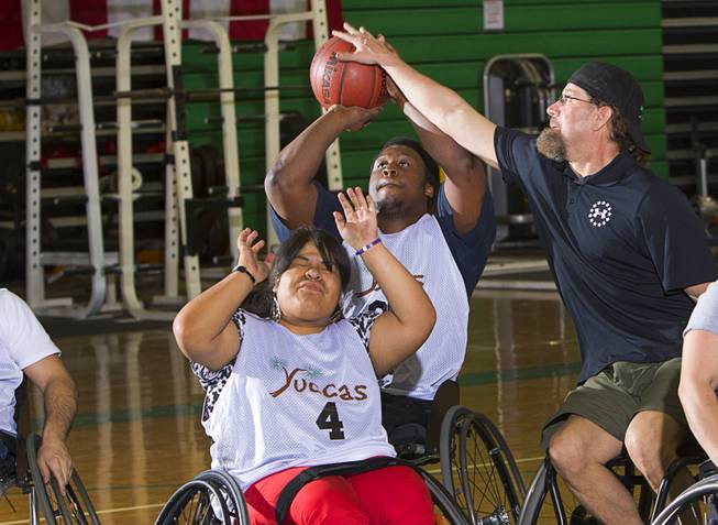Timothy Oliver gets stuffed by Jonathan Foster, during wheelchair basketball practice at Rancho High School Tuesday, Feb. 25, 2014. Cinthya Huendo is at lower left. Foster works for the City of Las Vegas and helps head the Las Vegas Paralympic Sport Club.