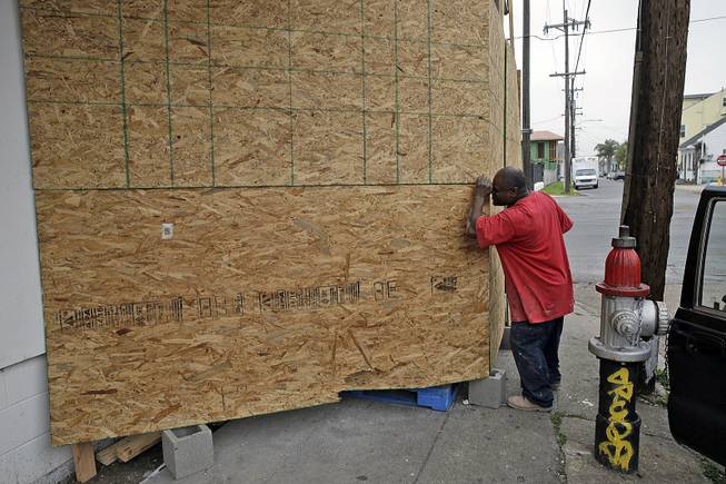 A passer-by peers into a plywood barrier now protecting a mural by the artist Banksy, in New Orleans, Tuesday, Feb. 25, 2014. 