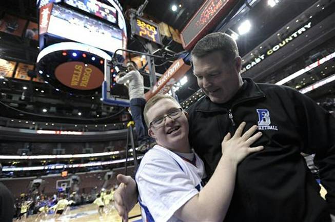 Kevin Grow hugs his Bensalem High basketball coach John Mullin before an NBA game between the Philadelphia 76ers and the Cleveland Cavaliers on Tuesday, Feb. 18, 2014, in Philadelphia. Kevin had been signed by the Philadelphia 76ers to a ceremonial two-day contract. Next, he’ll play with the Harlem Globetrotters.