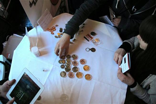 In this Feb. 12, 2014 file photo, attendees of the Inside Bitcoins conference in Berlin examine Bitcoin buttons. The website of major Bitcoin exchange Mt. Gox is offline amid reports it suffered a debilitating theft of the virtual currency, and the URL of the Tokyo-based outfit returns a blank page on Tuesday, Feb. 25, 2014.