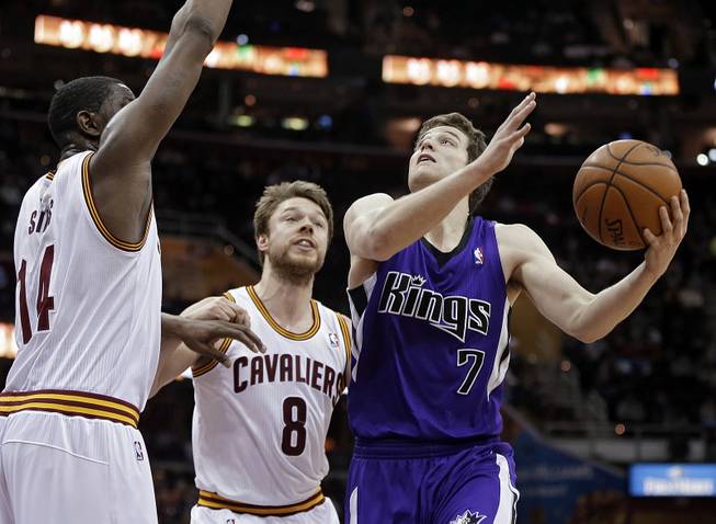 Sacramento Kings' Jimmer Fredette (7) goes in for a shot against Cleveland Cavaliers' Henry Sims, left, and Matthew Dellavedova (8), from Australia, during the second quarter of an NBA basketball game Tuesday, Feb. 11, 2014, in Cleveland.