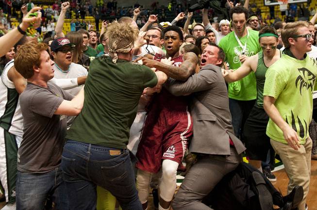New Mexico State's Daniel Mullings, at center in red and white jersey, is involved in a brawl involving players and fans who came onto the court when New Mexico State guard K.C. Ross-Miller hurled the ball at Utah Valley's Holton Hunsaker seconds after the Wolverines' 66-61 overtime victory against the Aggies in Orem, Utah.