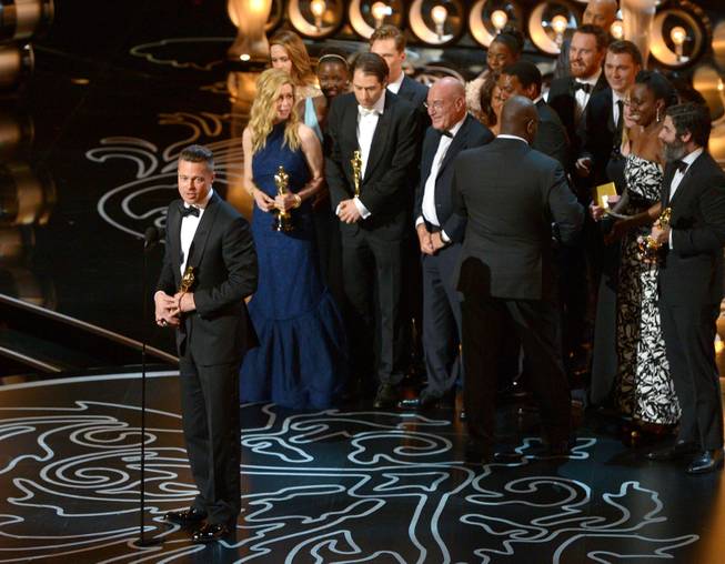 Brad Pitt, left, speaks as he and the cast and crew of "12 Years a Slave" accept the award for the best picture during the Oscars at the Dolby Theatre on Sunday, March 2, 2014, in Los Angeles.  (Photo by John Shearer/Invision/AP)