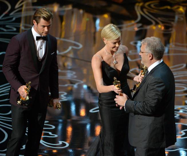 Presenters Chris Hemsworth, left, and Charlize Theron, center, present Skip Lievsay with the award for best sound mixing for "Gravity" during the Oscars at the Dolby Theatre on Sunday, March 2, 2014, in Los Angeles.  (Photo by John Shearer/Invision/AP)