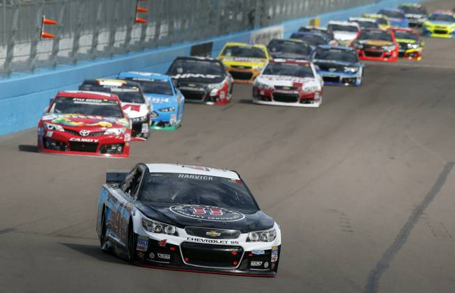 Kevin Harvick leads a group of cars into Turn 1 during the NASCAR Sprint Cup Series auto race Sunday, March 2, 2014, in Avondale, Ariz.