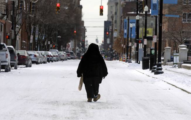 A pedestrian walks in the middle of a snow covered street, Monday, March 3, 2014, in downtown Cincinnati. The area received from three to six inches of new snow. 