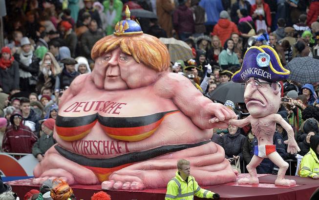 A carnival float caricating German chancellor Angela Merkel, left,  representing  the growing German economy, and a slim French president Francois Hollande during the traditional carnival parade in Duesseldorf, western Germany, on Monday, March 3, 2014. The foolish street spectacles in the carnival centers of Duesseldorf, Mainz and Cologne, watched by hundreds of thousands of people, are the highlights in Germany's carnival season on Rose Monday.  Words at left read: German Economy. 