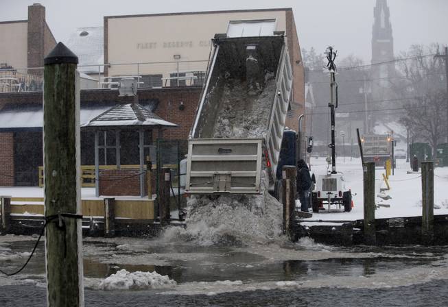 Workers with the City of Annapolis dump snow into Annapolis Harbor as snow continues to fall, Monday, March 3, 2014, in Annapolis, Md. 