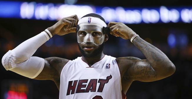 Miami Heat's LeBron James adjusts his protective mask during the first half of an NBA basketball game in Miami, Monday, March 3, 2014, against the Charlotte Bobcats. 