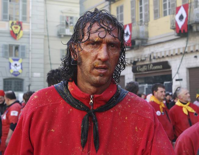 A man stands with his face covered of orange juice during an oranges battle part of Carnival celebrations, in the northern Italian Piedmont town of Ivrea, Tuesday, March 4, 2014. The traditional orange throwing battle has its roots in the middle of the XIXth century. 