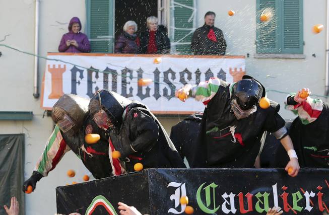 People wearing protection helmets and costumes throw oranges as part of Carnival celebrations in the northern Italian Piedmont town of Ivrea, Tuesday, March 4, 2014. The traditional orange throwing battle has its roots in the middle of the XIXth century.