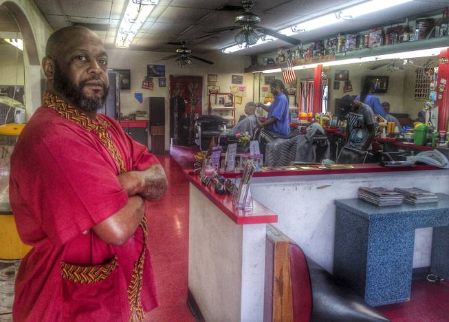 Michael Jones, left, co-owner of A Cut Above The Rest barbershop, located at Carson Avenue and 7th Street Wednesday, March 5, 2014. Tony Hsieh's Downtown Project has purchased the the barbershop's building but Jones says his business, which has a lease into 2015, is being allowed to stay. 