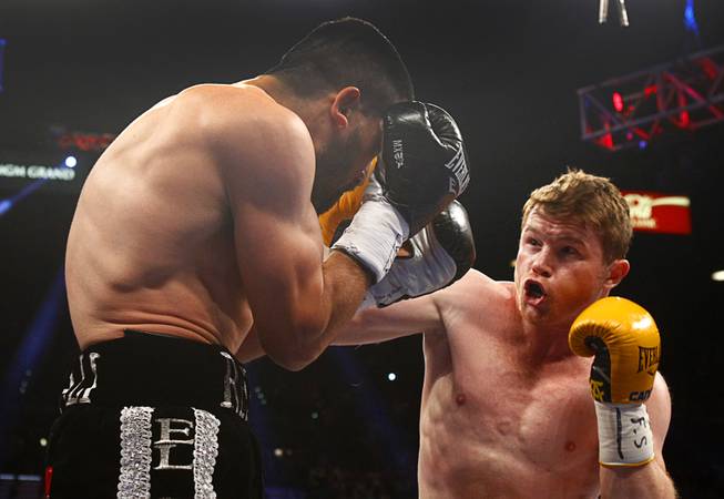 Alfredo Angulo, left, takes a punch from Canelo Alvarez, both of Mexico, during their super welterweight fight at the MGM Grand Garden Arena on Saturday, March 8, 2014. 