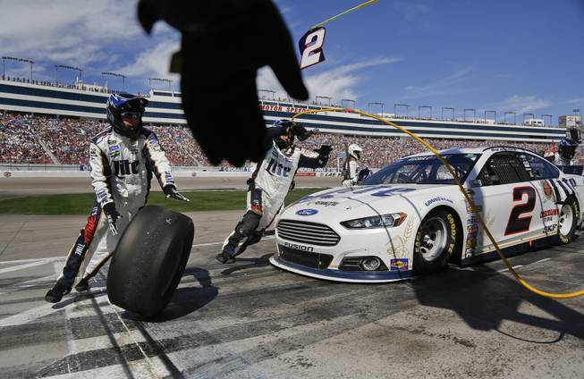 A pit crew member reaches to grab one of the used tires off of Brad Keselowski's car during a pit stop at a NASCAR Sprint Cup Series auto race on Sunday, March 9, 2014, in Las Vegas.