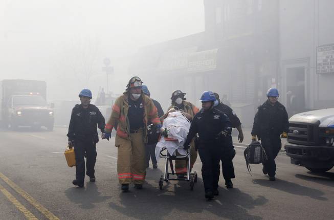 Rescue workers remove an injured person on a stretcher following a building explosion and collapse in East Harlem, Wednesday, March 12, 2014 in New York.