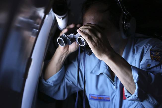 Vietnamese Air Force Col. Pham Minh Tuan uses binoculars on board a flying aircraft during a mission to search for the missing Malaysia Airlines flight MH370 in the Gulf of Thailand, Thursday, March 13, 2014. 