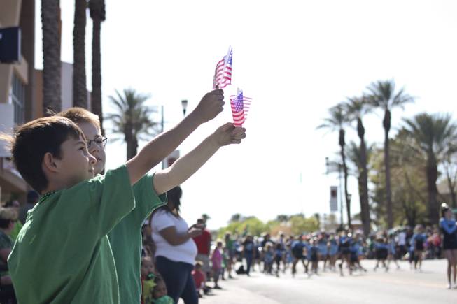 Taylor Ray, left, and Dayton Dube, glasses, hold up their American flags during the annual St. Patrick's Day parade in Henderson Saturday, March 15, 2014.