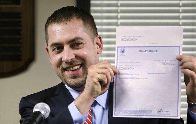 In this March 5, 2014, file photo, Sean Green displays his newly-issued Washington state legal marijuana license in Olympia, Wash.