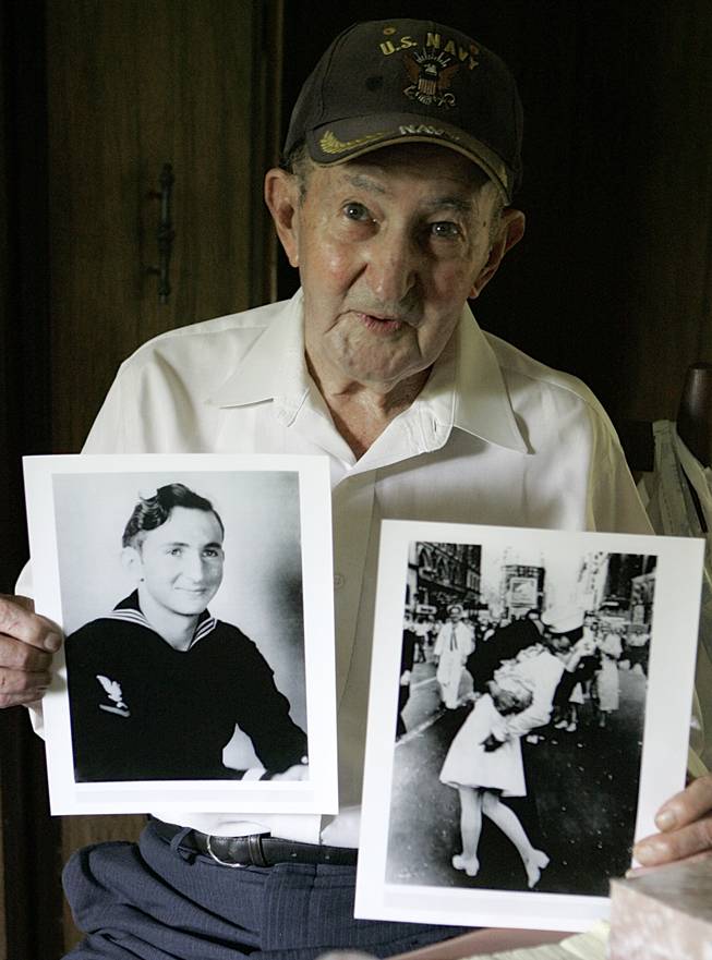 In this July 31, 2007, file photo, Glenn McDuffie holds a portrait of himself as a young man, left, and a copy of Alfred Eisenstaedt's iconic Life magazine shot of a sailor, who McDuffie claims is him, embracing a nurse in a white uniform in New York's Times Square, at his Houston home.