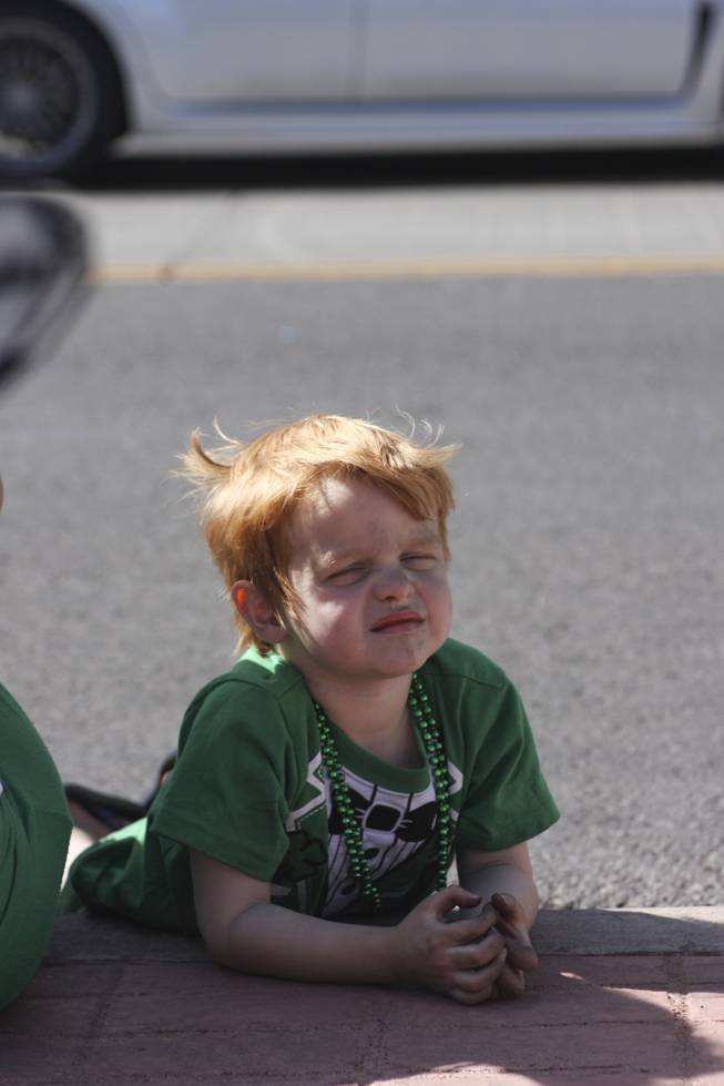 A little boy lays on the side walk looking on to the crowd towards the end of the annual St. Patrick's Day parade in Henderson Saturday, March 15, 2014.