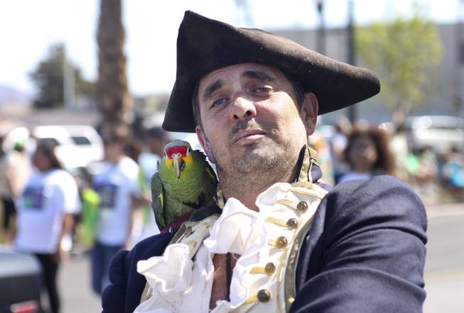A member from the Pirate Fest group poses with his parrot for the camera during the annual St. Patrick's Day parade in Henderson Saturday, March 15, 2014.