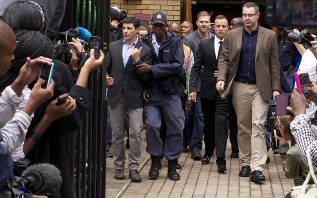 Oscar Pistorius, center, walks out of the high court in Pretoria, South Africa, on Friday, March 14, 2014. Pistorius is charged with murder for the shooting death of his girlfriend, Reeva Steenkamp, on Valentine's Day 2013.