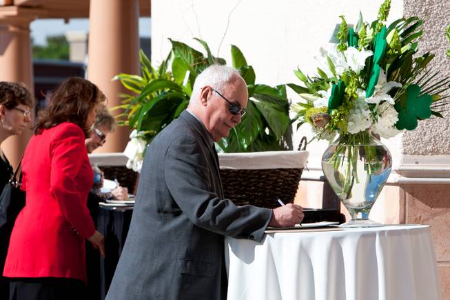 Surrounded by green floral arrangements and shamrocks, Steven Green signs a guestbook while attending the memorial mass for John Davis "Jackie" Gaughan held at St. Viator Catholic Church in Las Vegas on St. Patrick's Day, March 17, 2014.