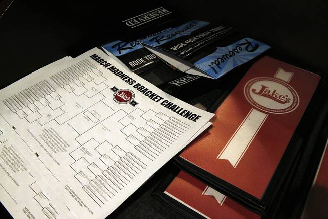 A stack of blank NCAA brackets sits with menus, available to patrons at Jake's sports bar, in Denver, Monday, March 17, 2014. 