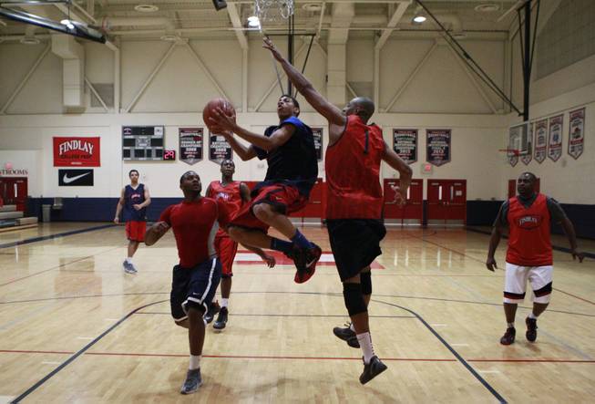 Findlay Prep guard Derryck Thornton Jr. drives to the basket while being defended by coaches Rodney Haddix, left, and Jerome Williams during practice Tuesday, March 18, 2014.