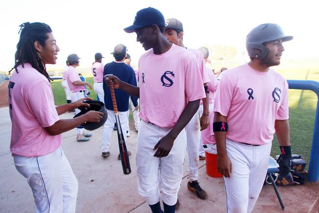 Canyon Springs outfielder Rashaad Jones hands his bat to a teammate during their game against Western Wednesday, March 19, 2014. The Pioneers wore pink jerseys for the game for cancer awareness and to honor parents of two of the players who died from cancer in the past year.