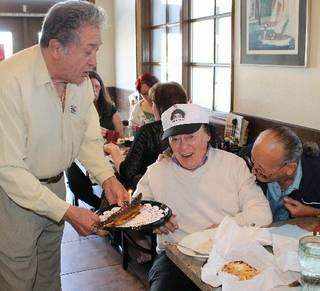Italian-American Club President Nelson Sardelli presents comedy legend Marty Allen with a smoked whitefish complete with candle for Allen's 92nd birthday at Bagel Delicatessen.