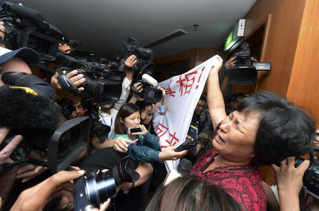 A Chinese relative of passengers aboard a missing Malaysia Airlines plane cries as she holds a banner in front of journalists reading 'We are against the Malaysian government for hiding the truth and delaying the rescue. Release our families unconditionally!" at a hotel in Sepang, Malaysia, Wednesday, March 19, 2014.