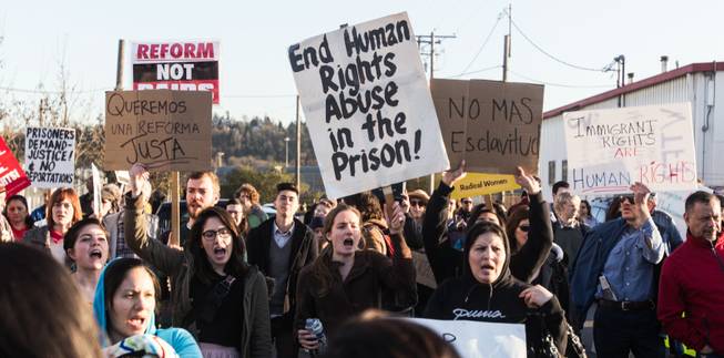 Demonstrators opposing deportations hold up signs while chanting in English and Spanish outside of the Northwest Detention Center in Tacoma, Wash. Tuesday, March 11, 2014.