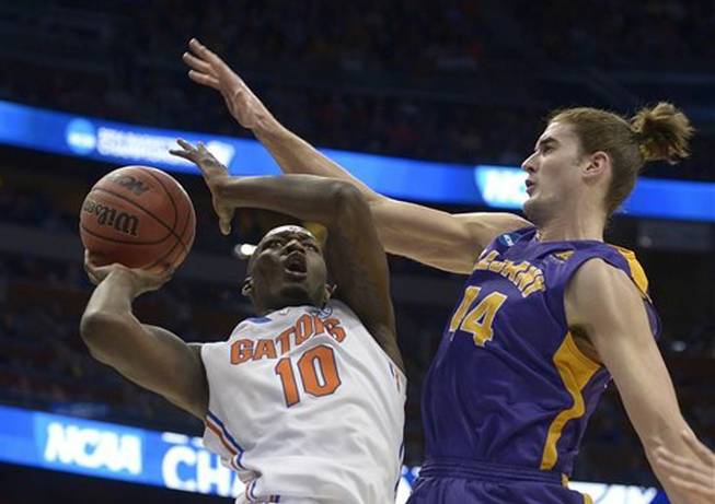 Albany center John Puk (44) fouls Florida forward Dorian Finney-Smith (10) during the first half of a second-round game in the NCAA college basketball tournament on Thursday, March 20, 2014, in Orlando, Fla.