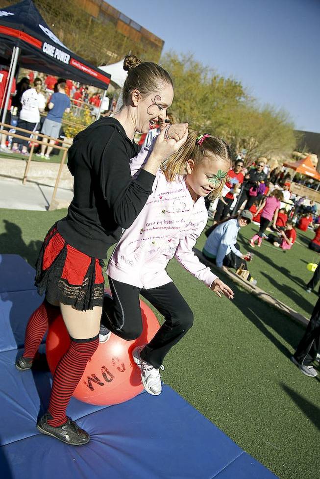 A performer helps a child balance at one of the interactive stations at the Run Away with Cirque du Soleil 5K Run and One-Mile Fun Walk at the Springs Preserve on Saturday, March 15, 2014.
