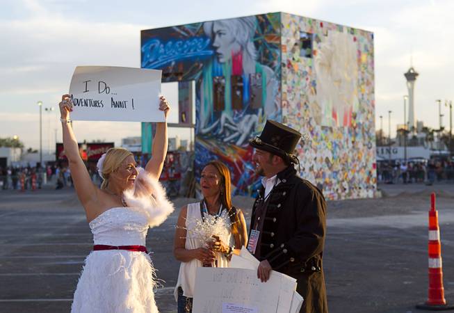 Betsy Donat (L) and Christian Ardita exchange wedding vows before the burning of the Life Cube (background), an interactive community art installation, in downtown Las Vegas, Friday March 21, 2014. Donna Manto looks on at center. The Life Cube, a creation of artist Scott Cohen, was a 24-by-24-foot plywood cube, painted by artists and filled with notes from thousands of people.