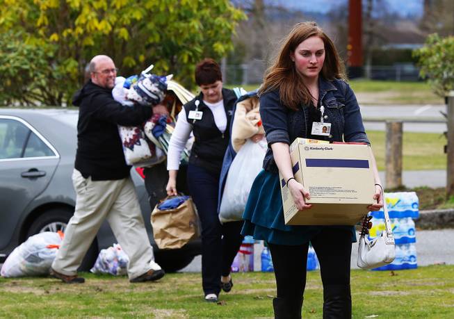 Claire Logan, at right, carries supplies to help set up an evacuation center at Post Middle School in Arlington to assist those impacted by the landslide on the North Fork of the Stillaguamish river March 22, 2014, in Arlington, Wash.