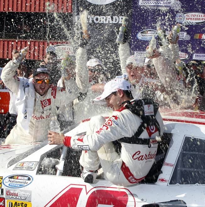 Kyle Larson, center, gets drenched by his team in Victory Circle after his win in the NASCAR Nationwide Series auto race in Fontana, Calif., on Saturday, March 22, 2014.