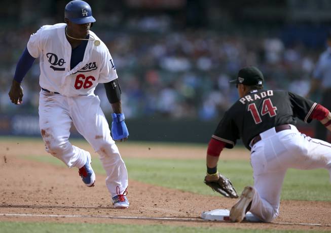 Los Angeles Dodgers' Yasiel Puig, left, is about to be tagged out at third base by the Arizona Diamondbacks' Marin Prado during the second game of the two-game Major League Baseball opening series between the two teams at the Sydney Cricket ground in Sydney on Sunday, March 23, 2014.