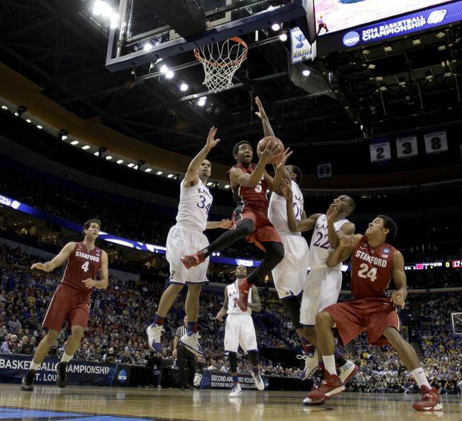 Stanford's Chasson Randle (5) gets between Kansas's Perry Ellis (34) and Tarik Black to shoot during the first half of a third-round game at the NCAA college basketball tournament Sunday, March 23, 2014, in St. Louis.