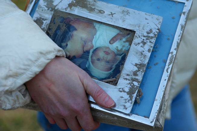 A woman holds family photos pulled from the rubble at the site of Saturday's fatal mudslide near Oso, Wash., Sunday, March 23, 2014.