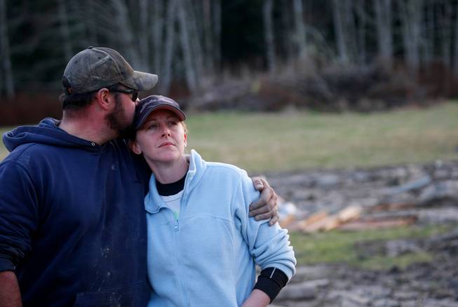Volunteers Frank and Rhonda Cook watch as the final body they recovered Sunday afternoon is lifted into a helicopter on the east side of Saturday's fatal mudslide near Oso, Wash. The couple started at 6 a.m. searching the area Sunday, March 23, 2014. 