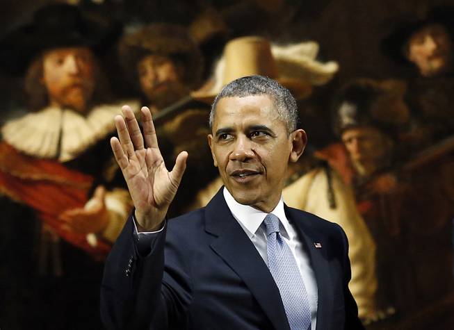 U.S. President Barack Obama waves in front of  Dutch master Rembrandt's The Night Watch painting during a visit to the Rijksmuseum in Amsterdam, Netherlands, Monday, March 24, 2014. Obama will attend the two-day Nuclear Security Summit in The Hague. 