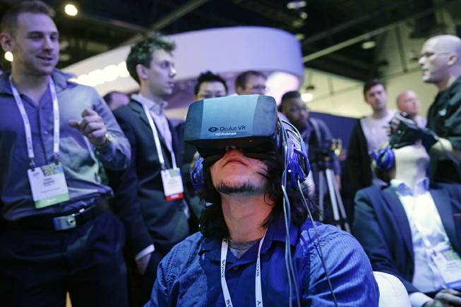 Show attendees play a video game wearing Oculus Rift virtual reality headsets at the Intel booth at the International Consumer Electronics Show in Las Vegas, Jan. 7, 2014. Facebook said Tuesday, March 25, 2014, it has agreed to buy Oculus for $2 billion. 