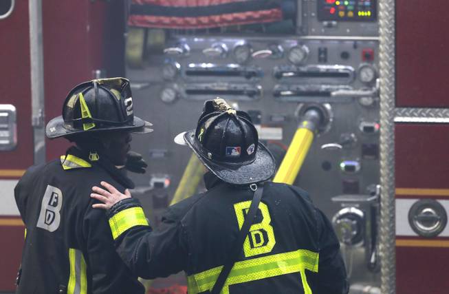 A firefighter places his hand on the shoulder of another at the scene of a multi-alarm fire at a four-story brownstone in the Back Bay neighborhood near the Charles River, Wednesday, March 26, 2014 in Boston. 